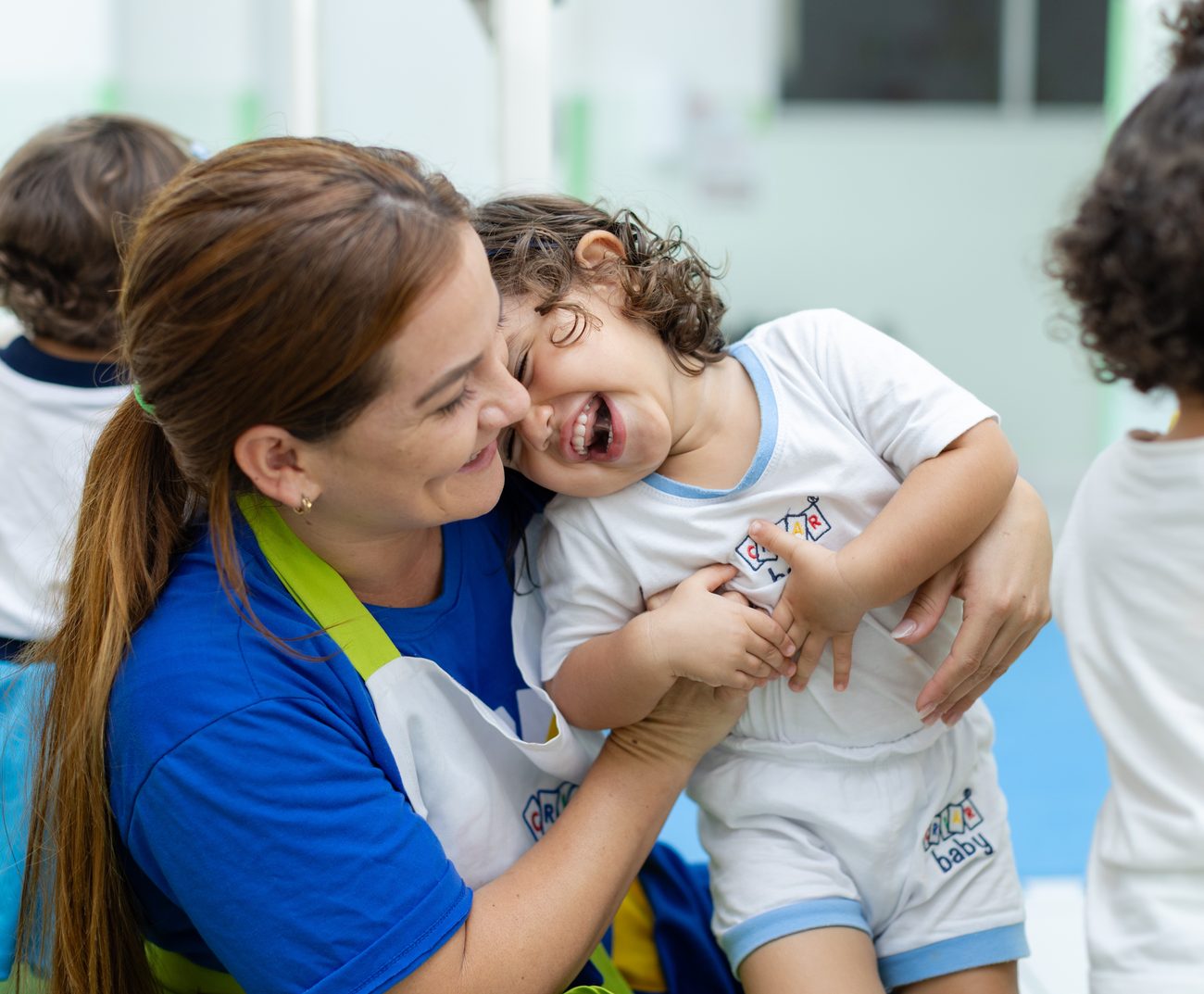 Educadora da Criar Baby no colo com uma criança sorrindo